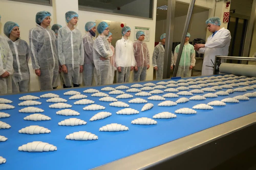 Ein Job, in dem es mehr zu tun gibt, als Croissants aufs Band zu legen: Azubi Jan Wiesenmüller (rechts) führt Schüler durch die Produktion.