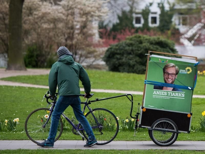 Ein Mann schiebt ein Fahrrad, mit dem er Plakate von Anjes Tjarks (Bündnis 90/Die Grünen) transportiert. Foto: Lukas Schulze/Archivbild