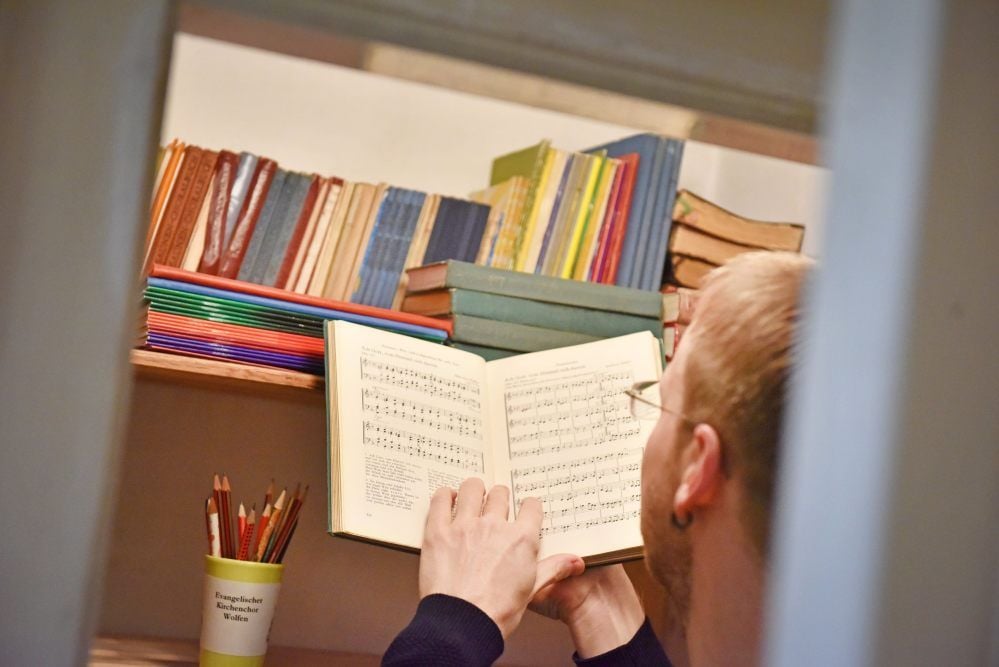 Rene Mangliers am Notenschrank in der Kirchengemeinde. Zu Hause ist der noch um einiges größer und bricht fast aus allen Nähten, wie er sagt.