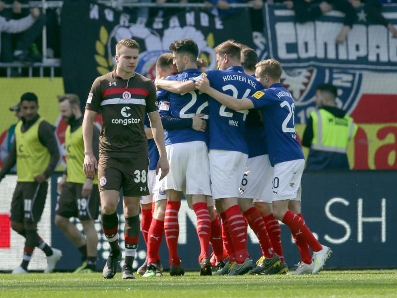 Die Kieler Spieler jubeln. In Unterzahl besiegen sie den FC St. Pauli mit 2:1. Foto: Frank Molter/dpa
