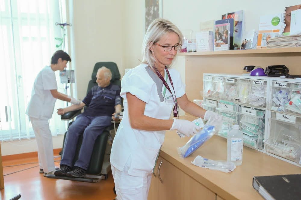 Franziska Held (rechts) bereitet eine Infusion vor, während Schwester Silke Walch einem Patienten eine Bluttransfusion anlegt.