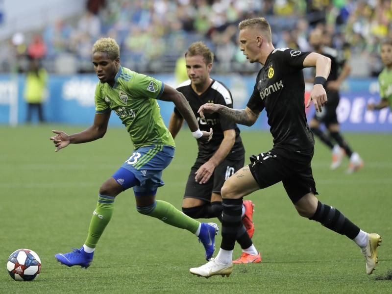 Joevin Jones von den Seaattle Sounders (l) wird von den BVB-Spielern Marius Wolf (r) und Mario Götze attackiert. Foto: Ted S. Warren/AP