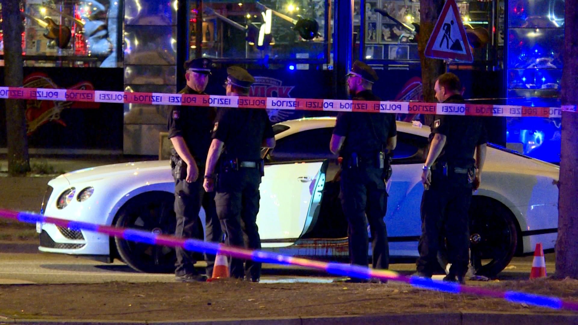 Polizisten stehen neben einem Auto auf dem Millerntorplatz, nachdem Schüsse gefallen waren. In Hamburg-St. Pauli ist ein Mann angeschossen und schwer verletzt worden.