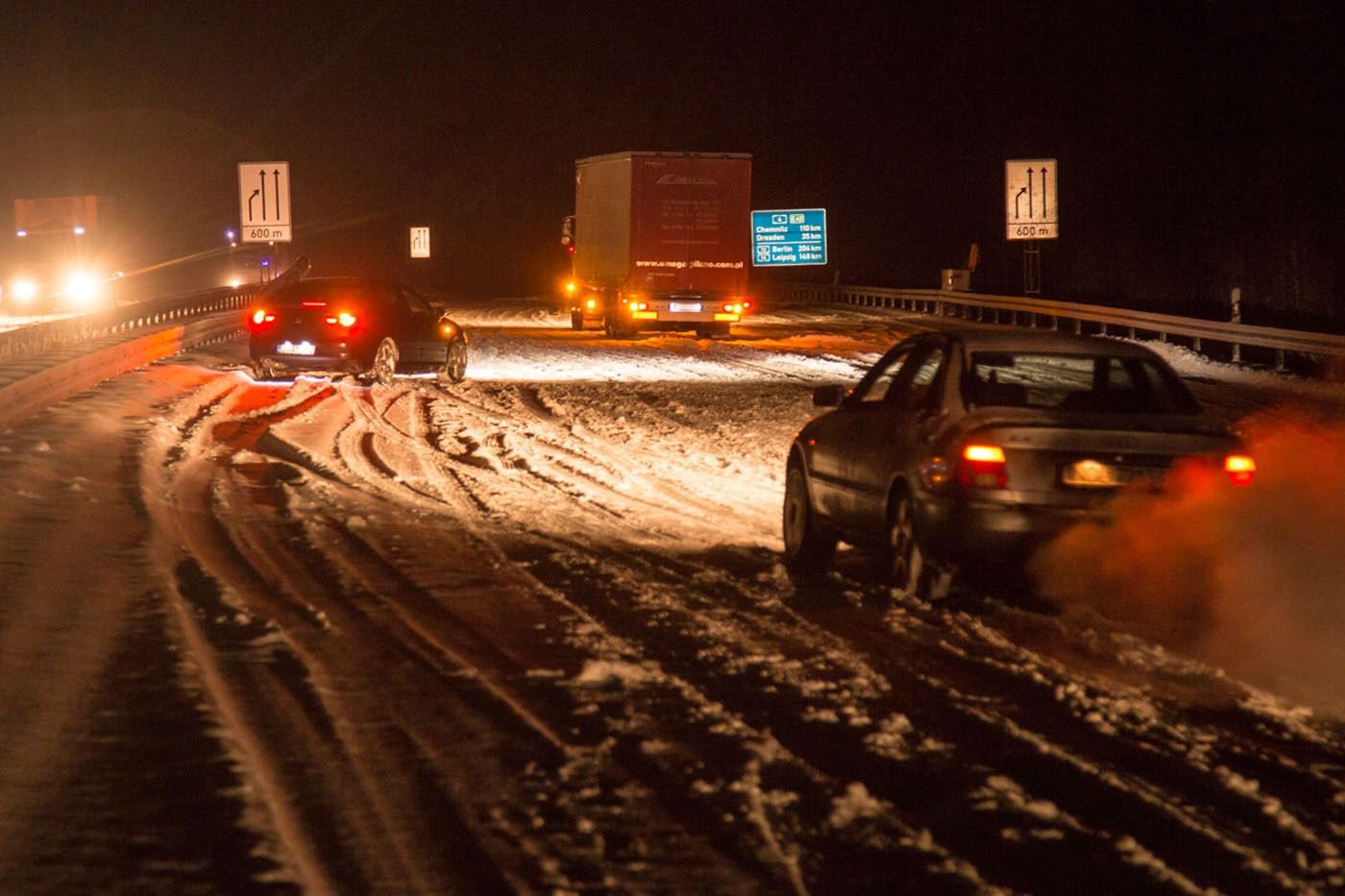 Zwei Autos und ein Lkw fahren auf der Autobahn A4 am Burkauer Berg langsam über die schneebedeckte Fahrbahn.