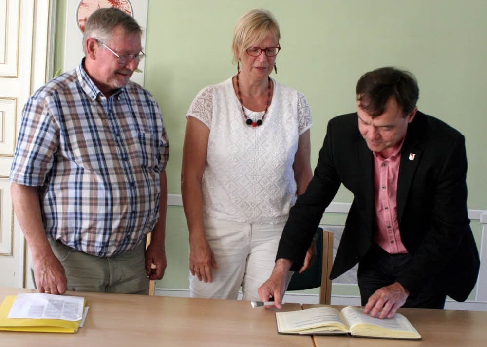 Bürgermeister Michael Jahn unterzeichnet den Ehrenbucheintrag für drei Jessener, die im April 1945 Häftlingen des Todesmarsches geholfen haben. Links neben ihm Ellen Fauser und Hans Richter von der IG Todesmärsche.