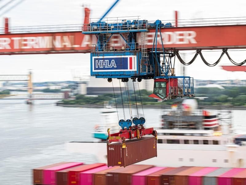 Ein Container wird auf dem Container Terminal im Hamburger Hafen mit einer Containerbrücke auf ein Schiff geladen. Foto: Daniel Reinhardt/dpa/Archivbild