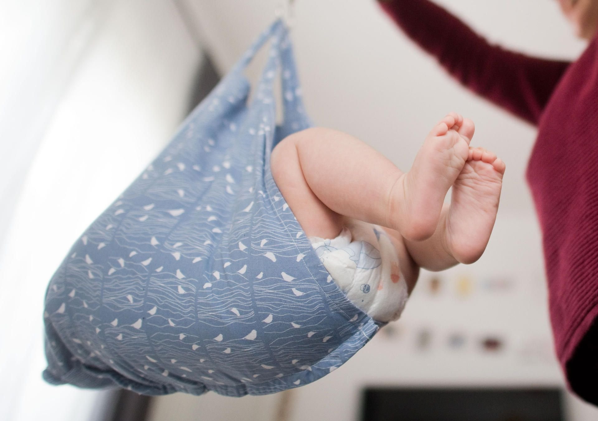 Eine Hebamme wiegt im Rahmen der Nachsorge ein Baby (gestellte Szene).