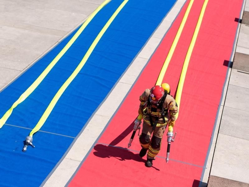 Ein Teilnehmer der Hamburger Firefighter Games zieht in voller Uniform Schläuche. Foto: Daniel Bockwoldt