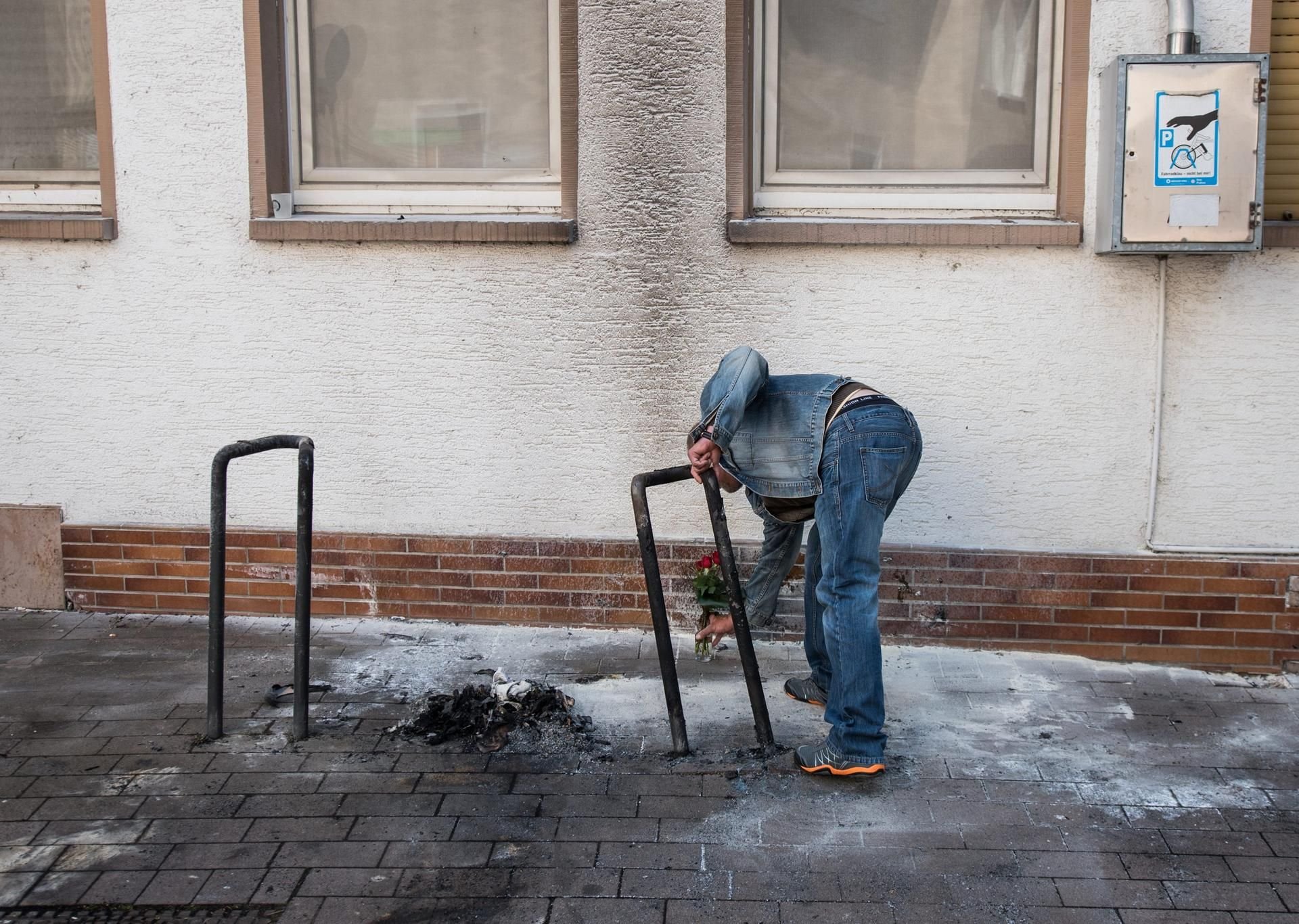 Ein obdachloser Freund legt an der Brandstelle in Gross-Gerau Blumen für den verbrannten Obdachlosen ab.