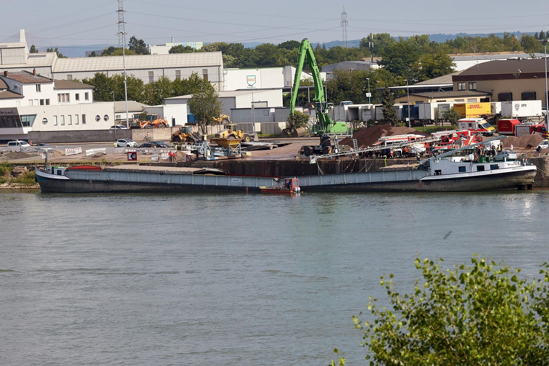Bergungskräfte sichern auf dem Rhein ein durchgeknicktes Frachtschiff.