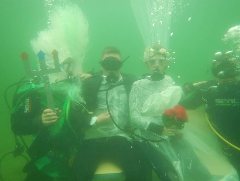 Die ungewöhnliche Hochzeitszeremonie unter Wasser mit dem Brautpaar, Trauzeugen und Neptun.