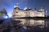 Der Reichstag, Sitz des Deutschen Bundestages, spiegelt sich am Wahlabend 2017 in Berlin in einer Regenpfütze.