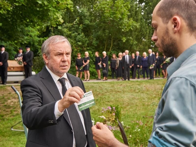 Als Geschäftsmann immer bereit: Georg Weiser (Joachim Król) gibt dem Friedhofsgärtner (Tom Lass) seine Visitenkarte. Foto: ZDF/Reiner Bajo