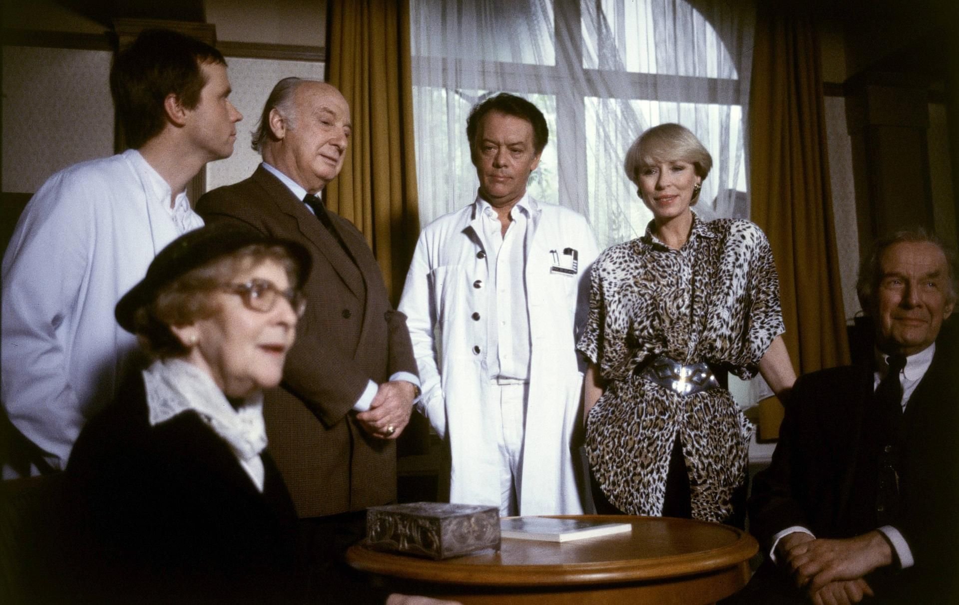 Szenenbild von „Die Schwarzwaldklinik“ (v.l.n.r.): Rose Renfe Roth (alte Dame), Michael Kausch (Dr. Engel), Alf Marholm (Klinikdirektor Mühlmann), Klausjürgen Wussow (Prof. Brinkmann), Karin Eckhold (Sekretärin, Frau Meis), Axel von Ambesser (der alte Herr, Landgerichtsrat Eckner).