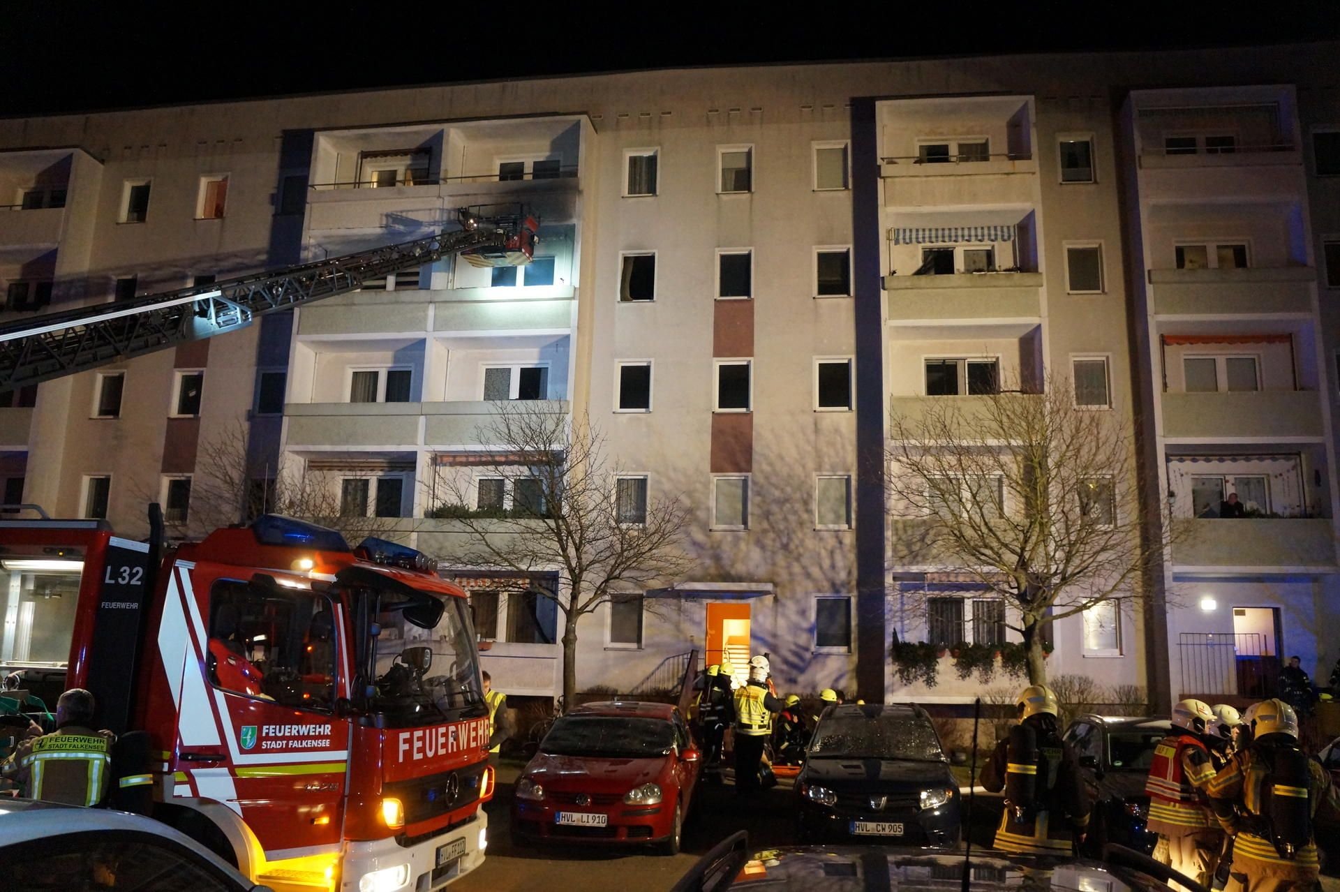 Feuerwehrmänner stehen vor einem Mehrfamilienhaus in Falkensee