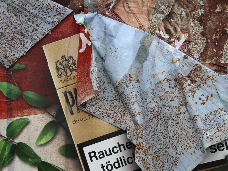 Ein Plakat mit Zigarettenwerbung löst sich von einer Plakatwand. Foto: picture alliance / dpa