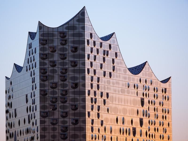 Die gläserne Fassade der Elbphilharmonie wird von der aufgehenden Sonne beleuchtet. Foto: Christian Charisius/Archiv