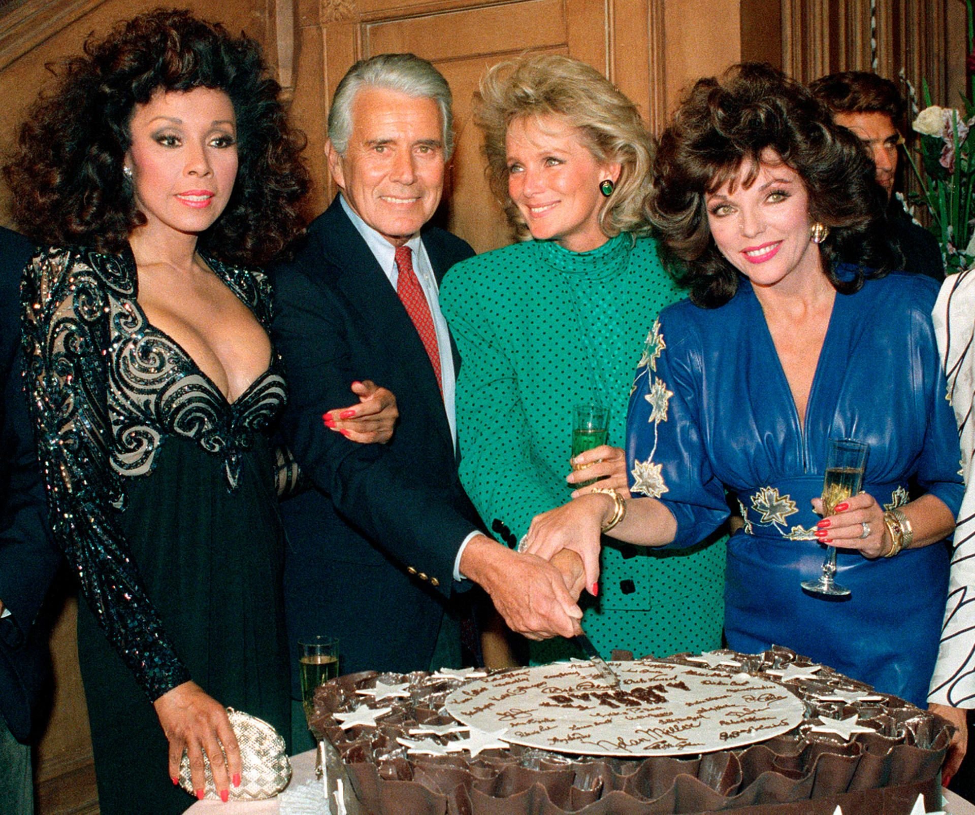 Die Schauspieler Diahann Carroll, John Forsythe, Linda Evans und Joan Collins (v.l.) aus der Hit-Serie „Der Denver-Clan“ (Original-Titel „Dynasty“) posieren beim Anschneiden eines Kuchens anlässlich der Produktion der 150. Folge der beliebten Serie.
