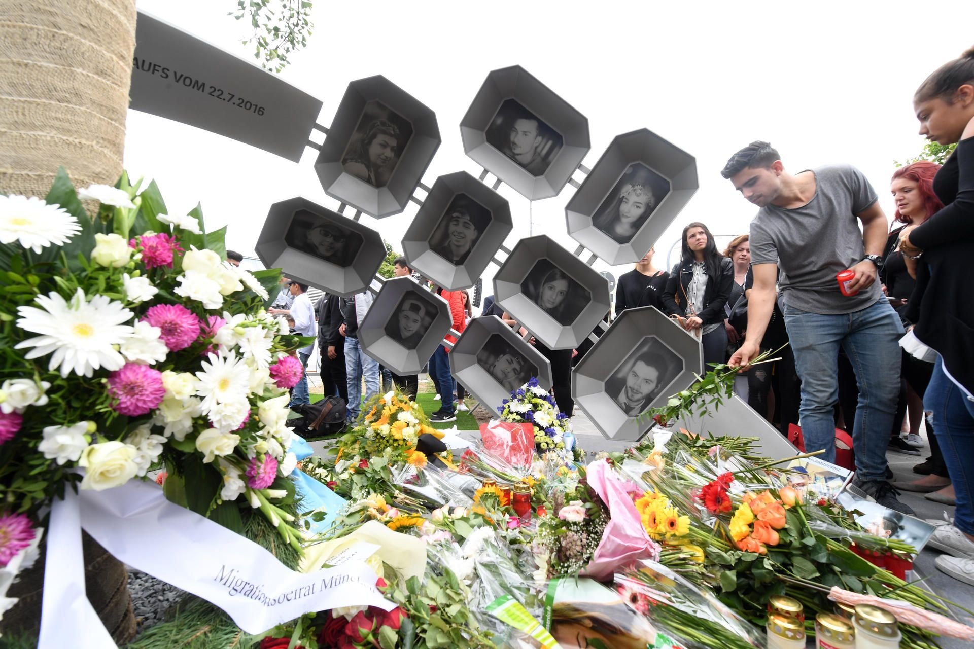 Besucher legen in München am Ende einer Gedenkveranstaltung Blumen am Denkmal nieder.