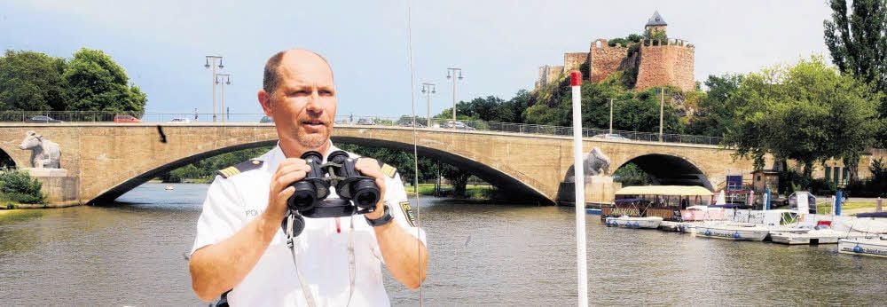 Ralph Rösiger kontrolliert die Lage am und auf dem Fluss. Von der Kröllwitzbrücke im Hintergrund springen immer wieder Leichtsinnige in die Saale.