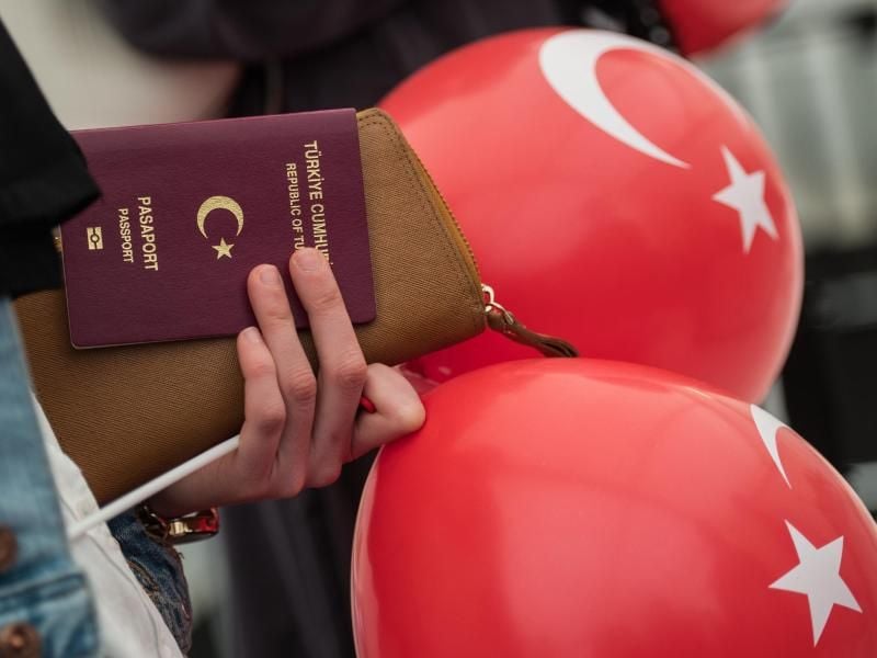 Eine Frau steht mit ihrem türkischen Pass und Ballons an einem Wahllokal an. Foto: Andreas Arnold