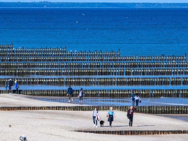 Spaziergänger am Strand von Koserow auf der Ostseeinsel Usedom. Foto: Jens Büttner/dpa-Zentralbild/dpa