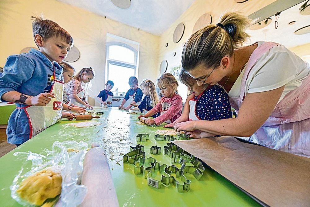 Caroline Kopelke vom Elternkuratorium (rechts) unterstützt die Drei- bis Sechsjährigen beim Backen in der Kinderlernküche.