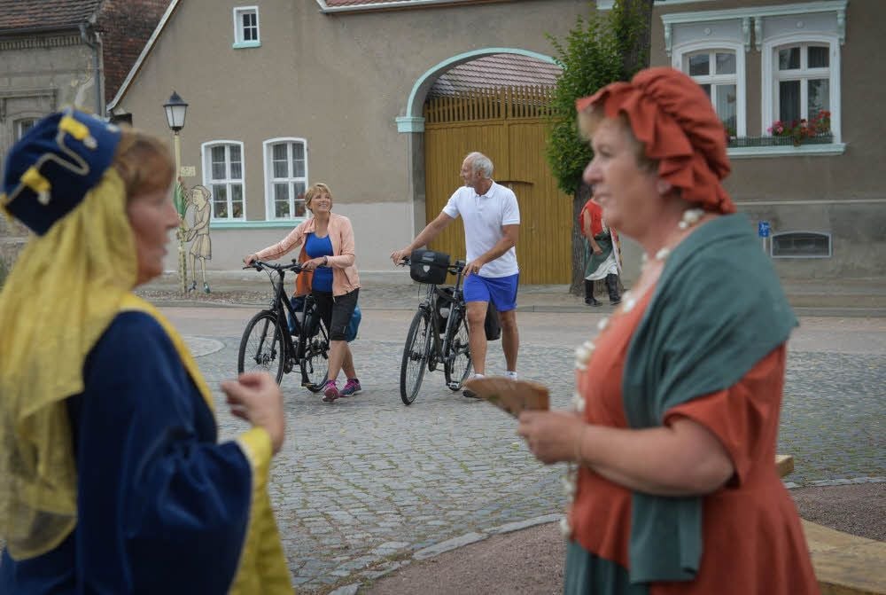 Drehort Reppichau: Mit den Rädern auf Entdeckungsreise sind Monika Herwig und Gerhard Stöhr. Im Eike-von-Repgow-Dorf treffen sie auch auf Fürstin Irmgard von Thüringen und auf eine Marketenderin. Vielleicht findet genau diese Einstellung ihren Weg in den neuen Imagefilm des Landkreises.