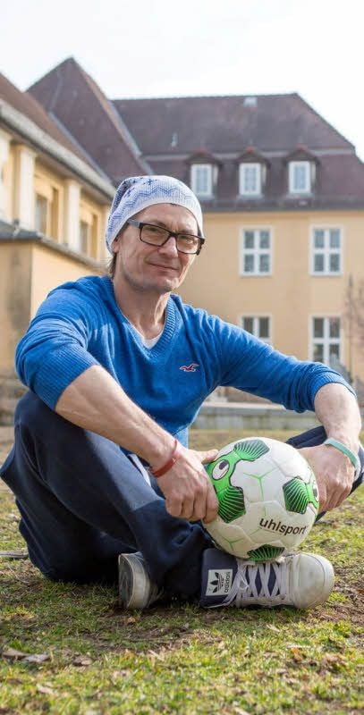 Mario Pacholski vom Frauen- und Kinderschutzverein sitzt hinter dem Haus der Jugend auf dem baldigen Bolzplatz..