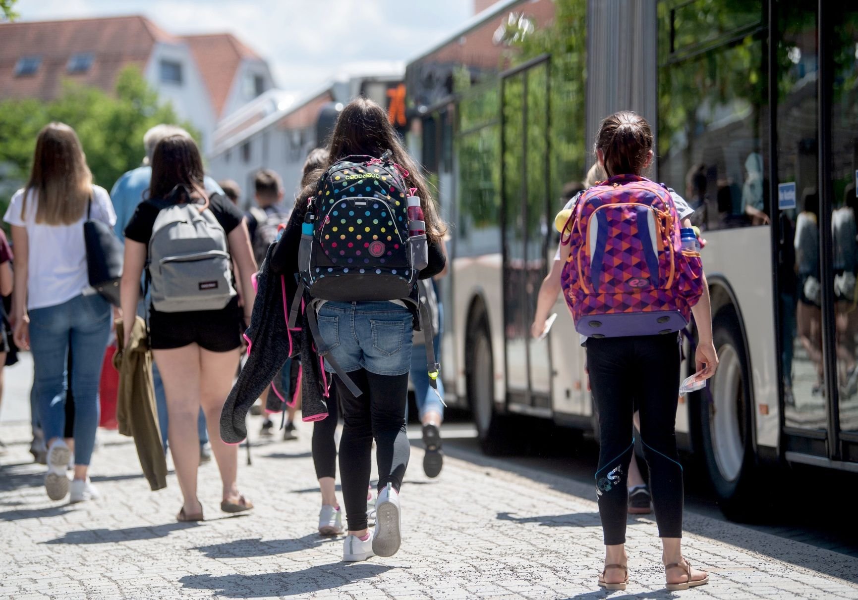 Schüler sind an einer Haltestelle auf dem Weg zu mehreren Schulbussen.