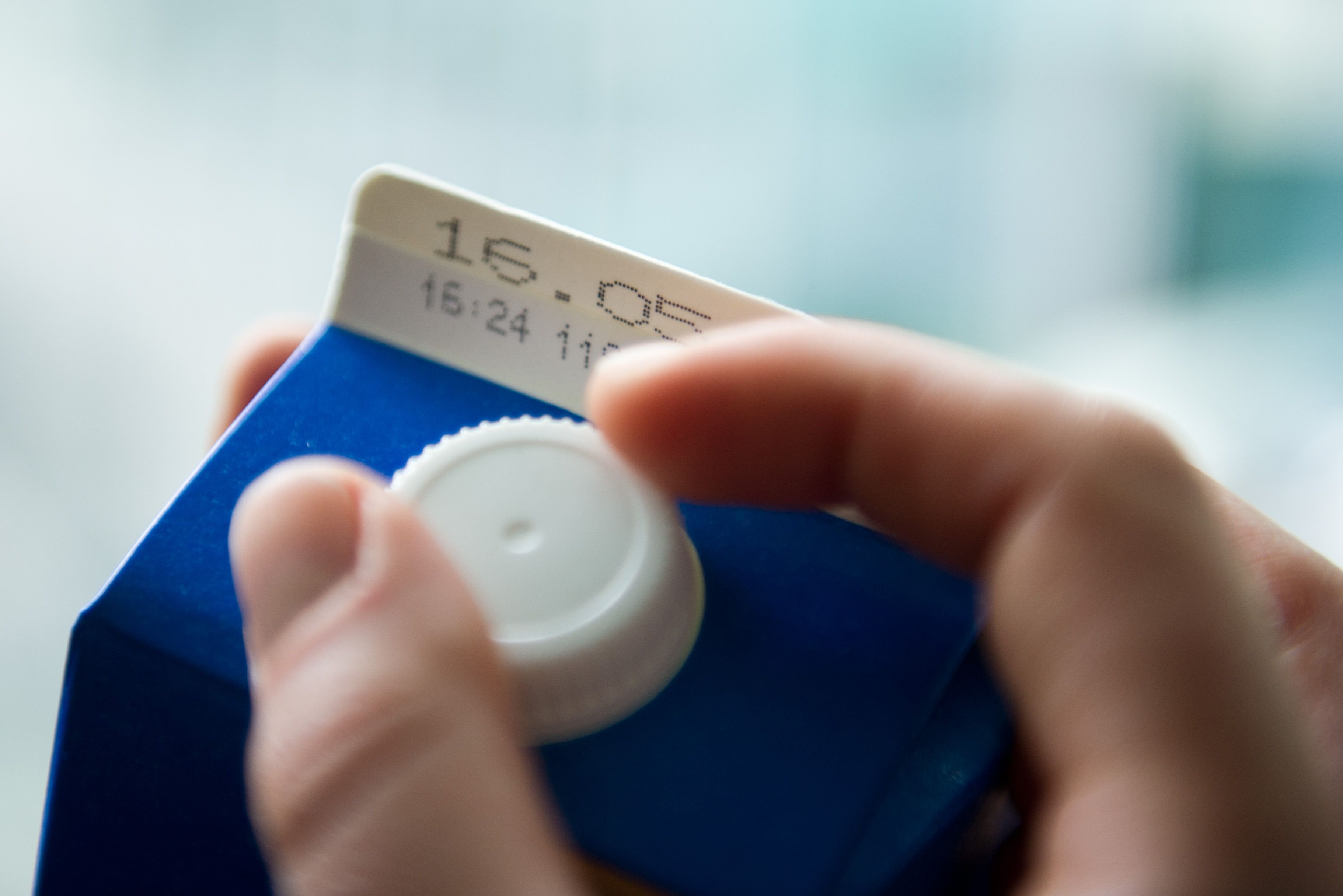 Eine Hand öffnet in Berlin einen Tetrapack Milch mit dem Mindesthaltbarkeitsdatum «16.05.».