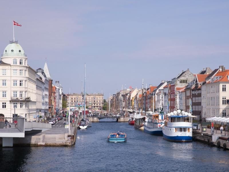 Ein kleines Ausflugsboot fährt in der Innenstadt von Kopenhagen in den Nyhavn. Foto: picture alliance / Christian Charisius/dpa/Archivbild