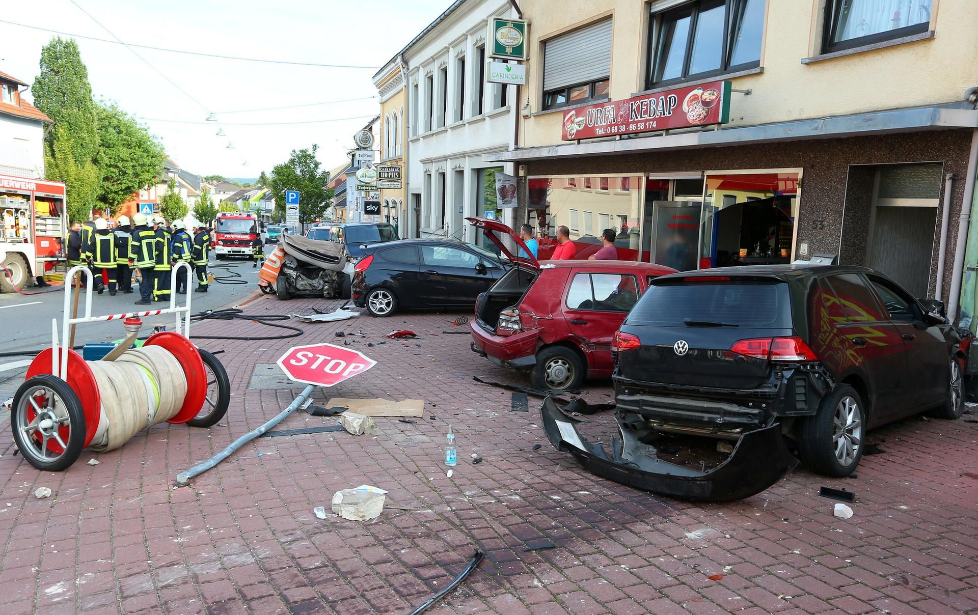 Ein Bild der Verwüstung bietet sich am 23. August in Saarwellingen (Saarland), nachdem ein 26 Jahre alter Mann aufgrund gesundheitlicher Probleme am Steuer seines Autos (ganz rechts) ungebremst gegen einen Wagen (links hinten neben der Gruppe von Feuerwehrleuten) raste, in dem eine Frau ums Leben kam.