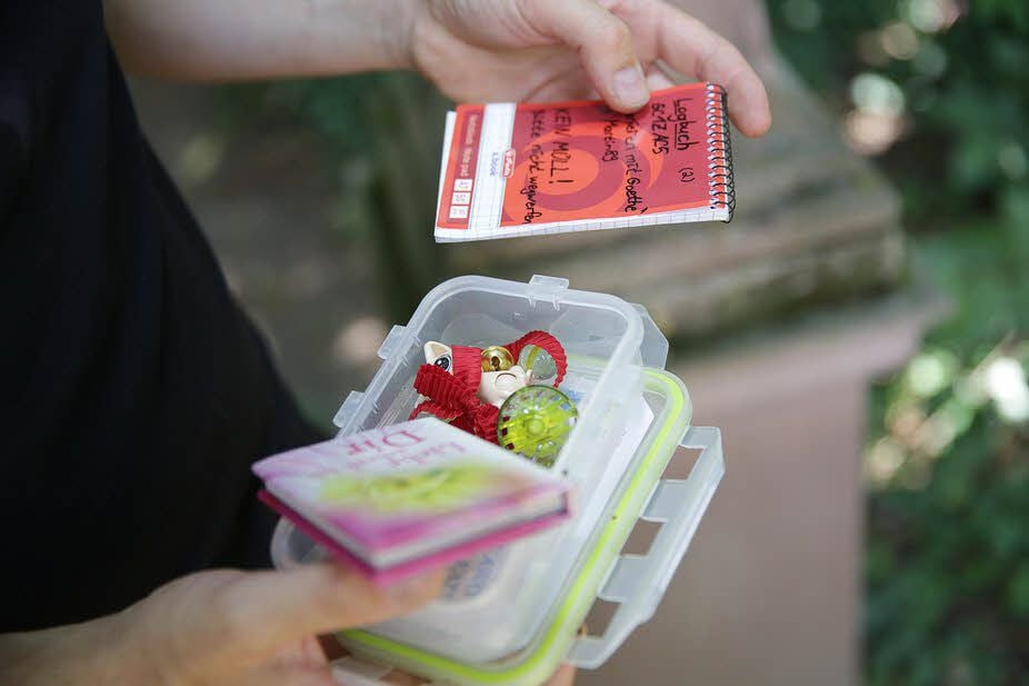 Der Cache-Behälter ist gefüllt mit einem Logbuch und Tauschgegenständen.