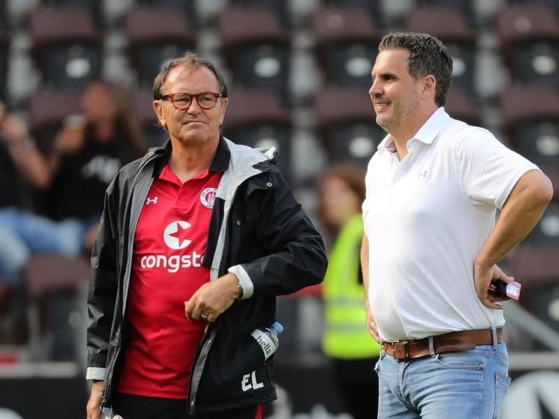 St. Paulis Sportdirektor Thomas Meggle (r) steht weiter zu Trainer Ewald Lienen. Foto: Christian Charisius