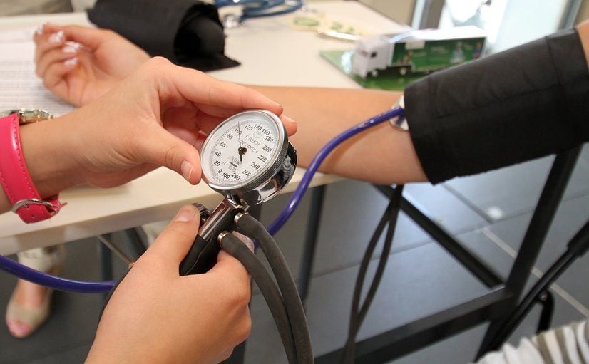 Mit einem Messgerät wird der Blutdruck eines Patienten gemessen.