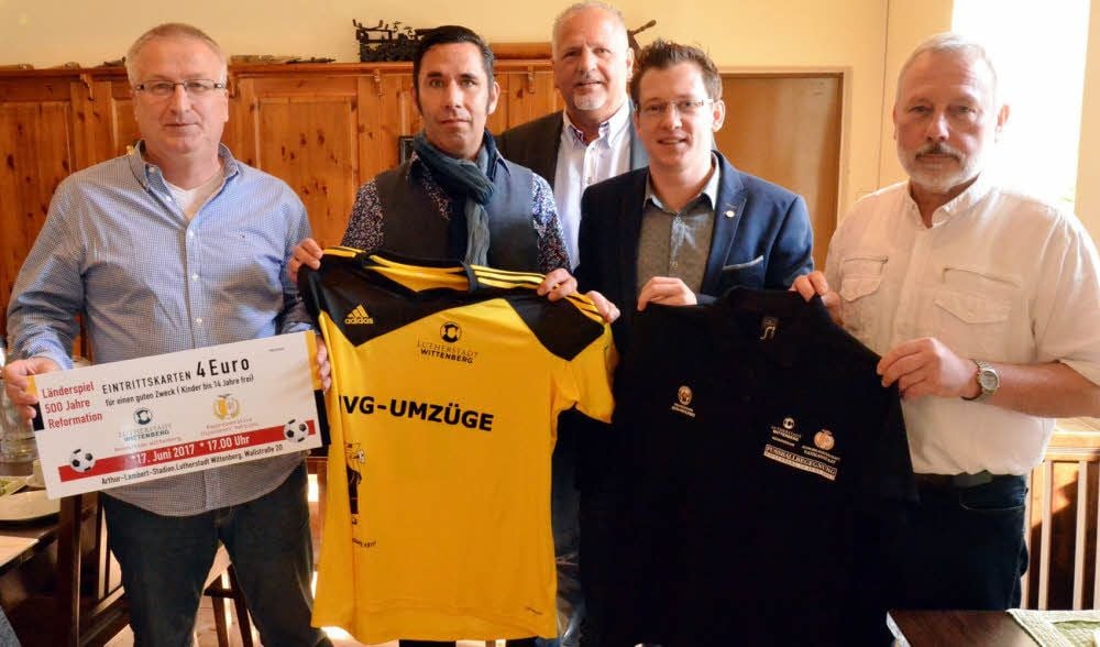 So sehen die Eintrittskarte, das schwarz-gelbe Spieltrikot, präsentiert von Kapitän Daniel Pflug (2. v. l.), und das Mannschaftsshirt aus. Coach Karl-Heinz Röthel wird am 17. Juni beim Rückspiel gegen die Vatikan-Auswahl aktiv von Trainerlegende Eduard Geyer unterstützt.