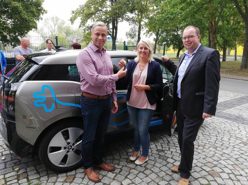 Julia Schibbe übergibt Dirk Kaufmann vom Bauamt der Gemeinde Elsteraue den Schlüssel für das Elektroauto. Michael Scheffler (rechts) ist der Kommunalberater der Envia M und ist der Ansprechpartner bei Fragen.
