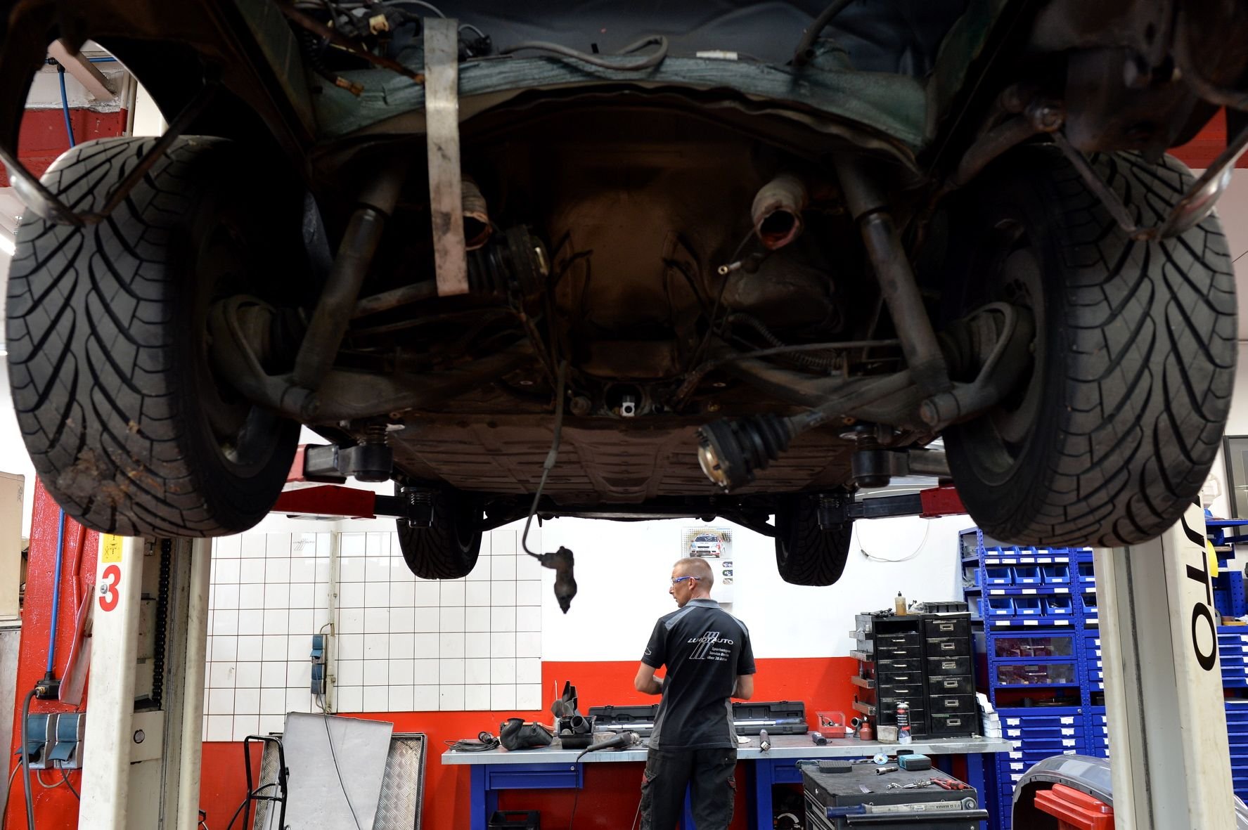 Ein Kfz-Mechaniker arbeitet in einer Werkstatt an einem Auto.