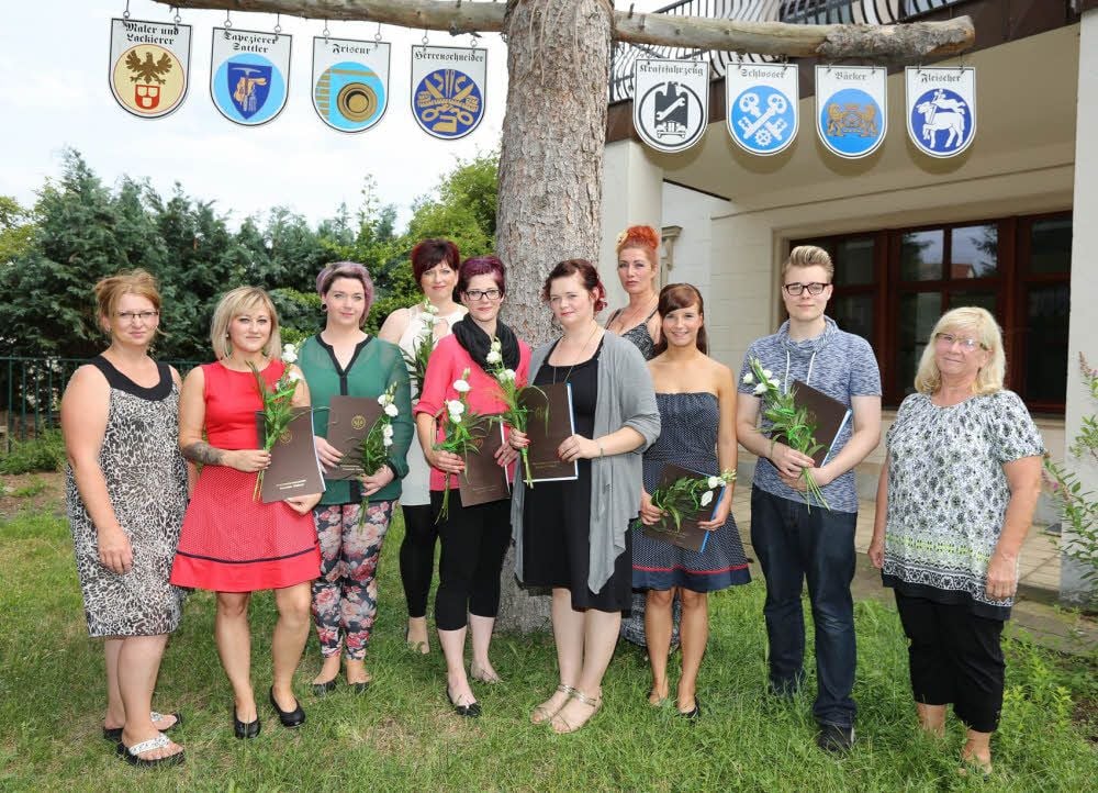 Die frischgebackenen Friseure freuen sich unter dem Zunftbaum über ihre erfolgreiche Ausbildung.