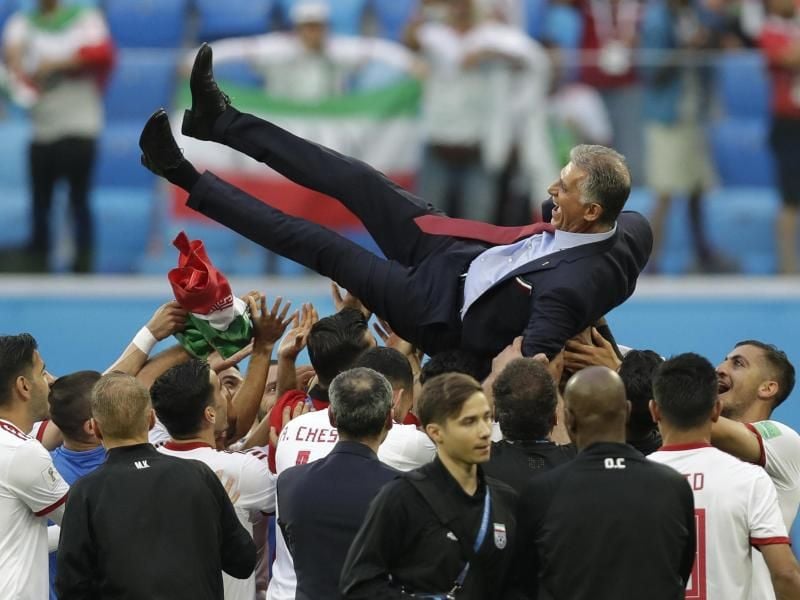 Irans Spieler lassen nach dem Sieg Trainer Carlos Queiroz hochleben. Foto: Andrew Medichini/AP