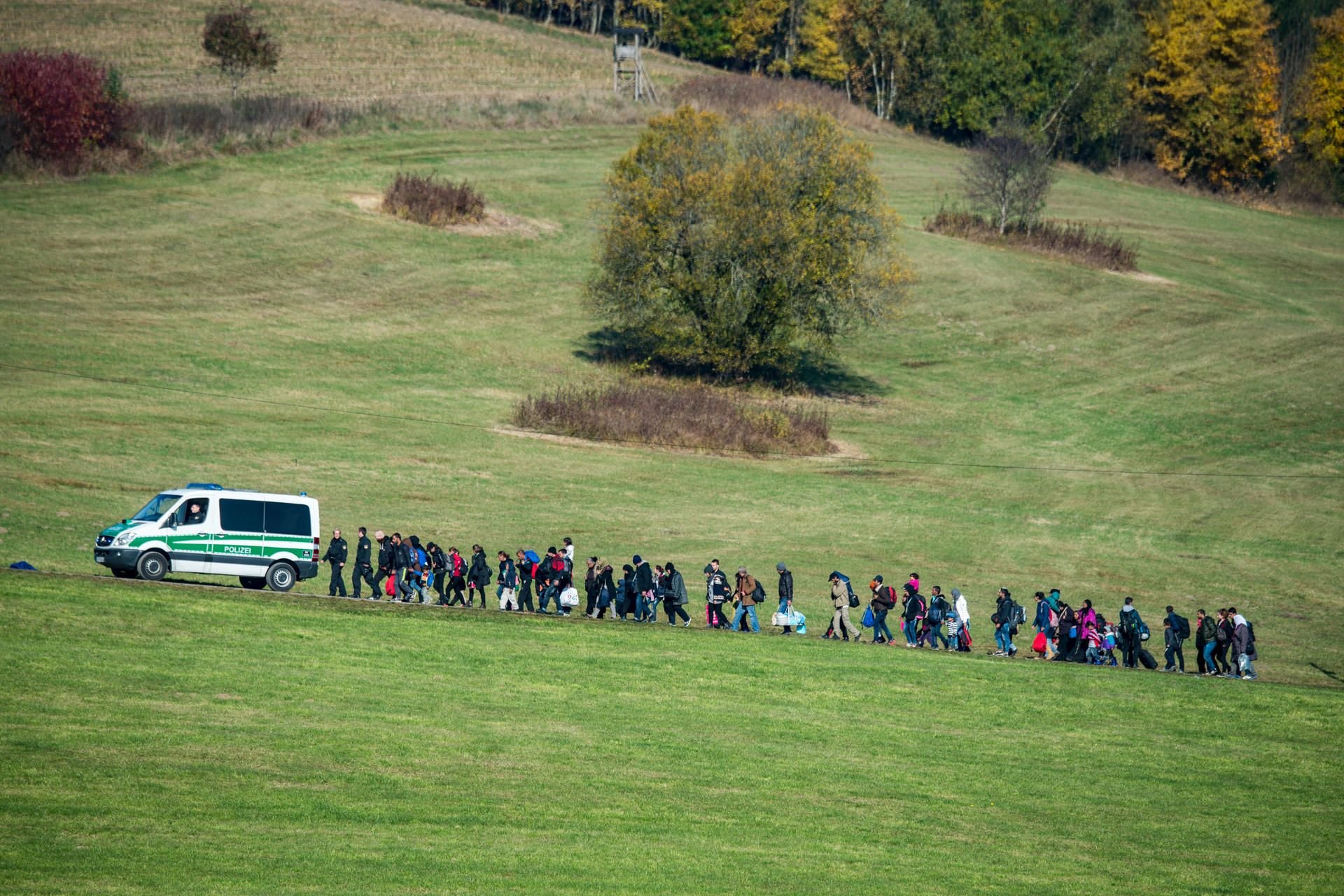 Flüchtlinge gehen im Oktober 2015 nahe Wegscheid (Bayern) hinter einem Fahrzeug der Bundespolizei.