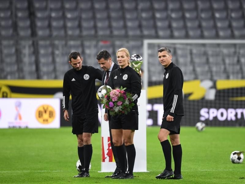 Die scheidende Schiedsrichterin Bibiana Steinhaus wurde vor dem Anpfiff von DFL-Boss Christian Seifert (2.v.l) mit Blumen bedacht. Foto: Sven Hoppe/dpa-Pool/dpa
