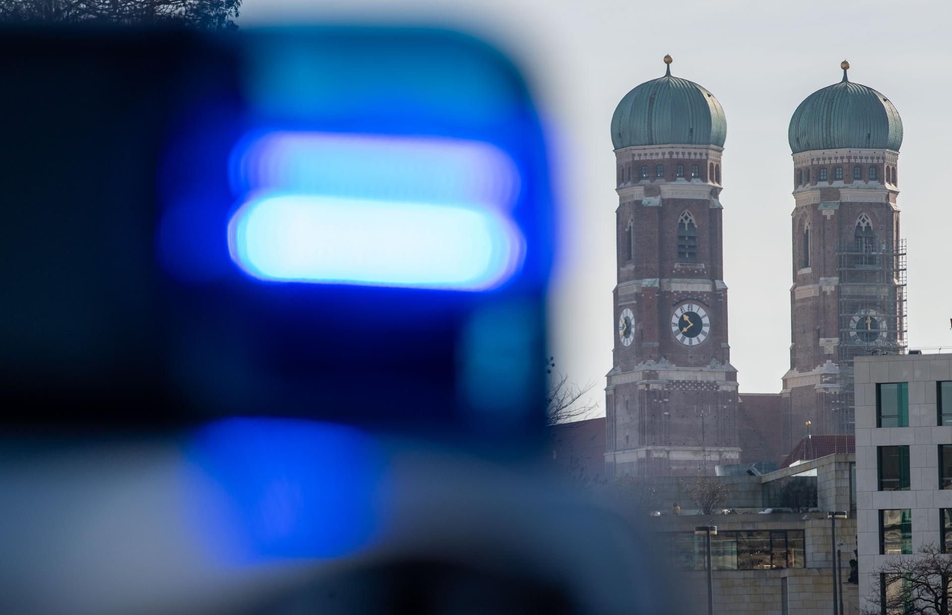 Ein Blaulicht einer Polizeistreife ist vor den Türmen der Frauenkirche in München zu sehen. (Symbolbild)