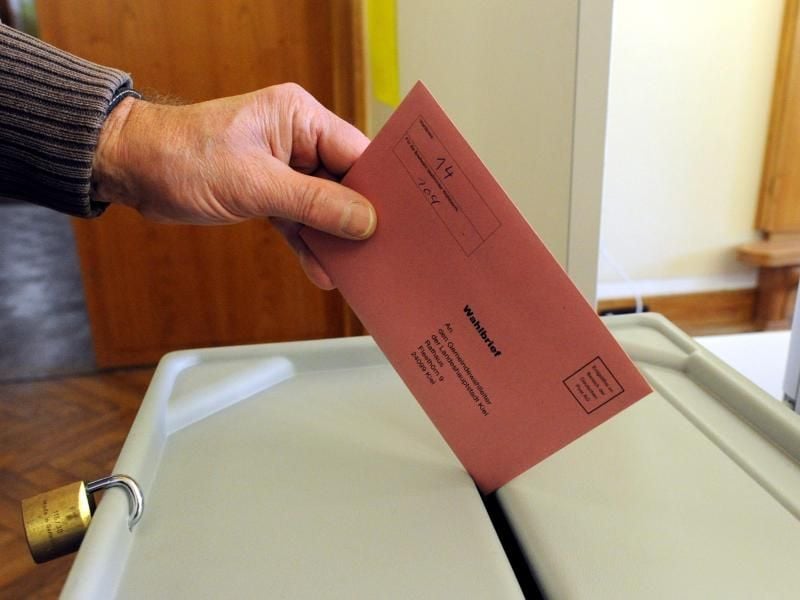 Ein Mann wirft im Rathaus Kiel seinen Stimmzettel in die Wahlurne. Foto: Carsten Rehder/Archiv