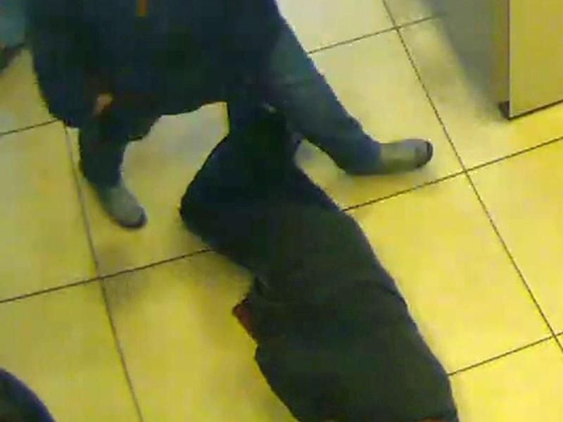 Das Foto der Polizei Essen zeigt Bankkunden, die im Vorraum einer Bank über einen hilflosen Mann hinwegsteigen. Foto: Polizei Essen