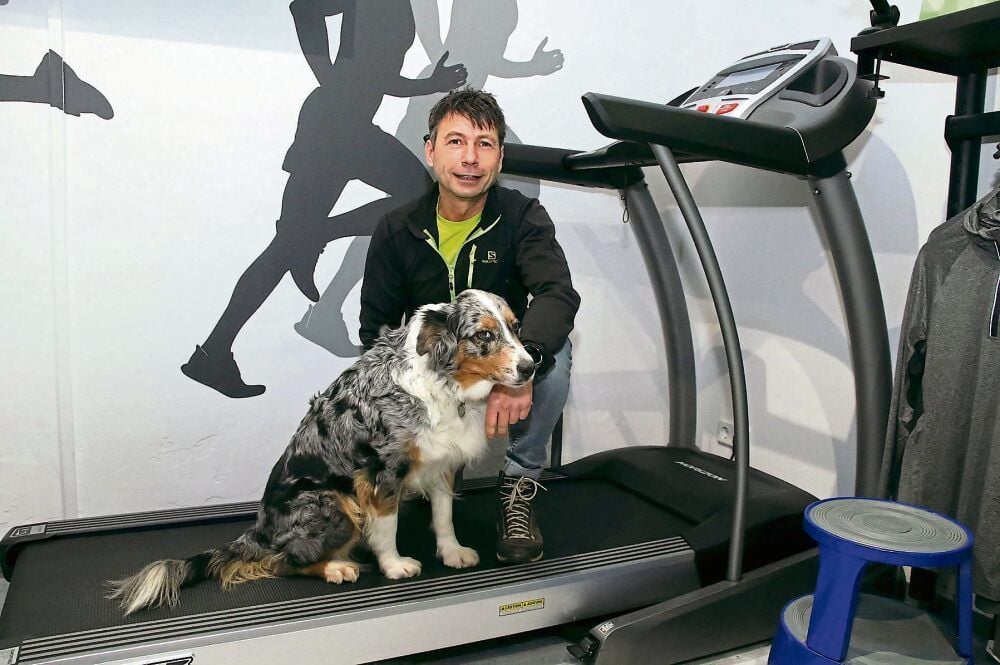 Andreas Liebig auf dem Laufband in seinem Sportgeschäft. Mit dabei seine treue Begleiterin: Australian-Shepherd-Hündin Dina.