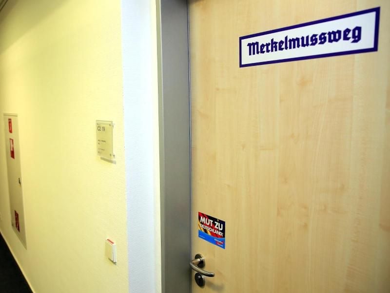 Ein Aufkleber „Merkelmussweg” klebt an der Tür von einem AfD-Abgeordneten. Foto: Peter Gercke/Archiv