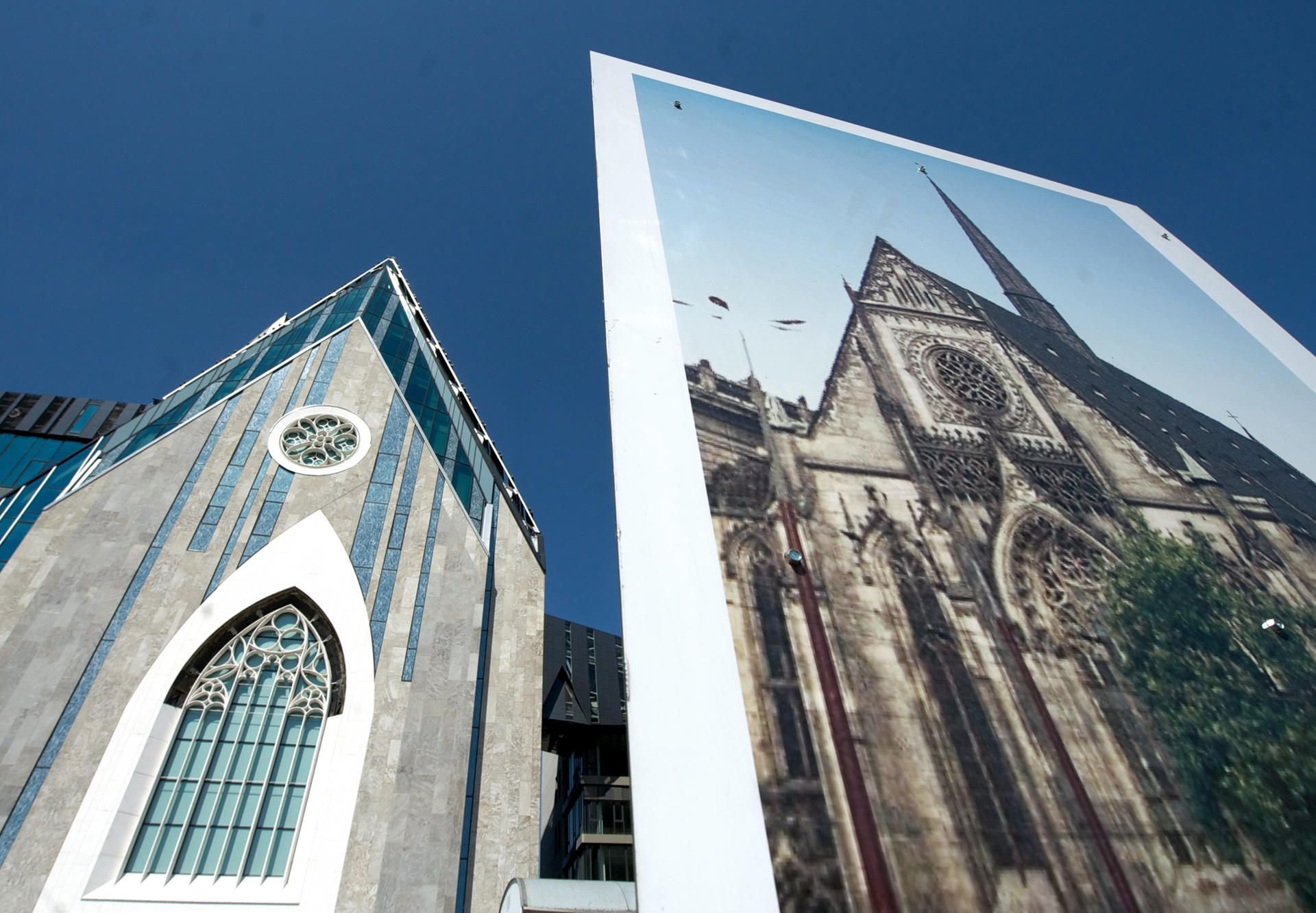 Das Paulinum der Leipziger Universität (l) ist neben einem Plakat mit einem Foto von der Universitätskirche Leipzig zu sehen.