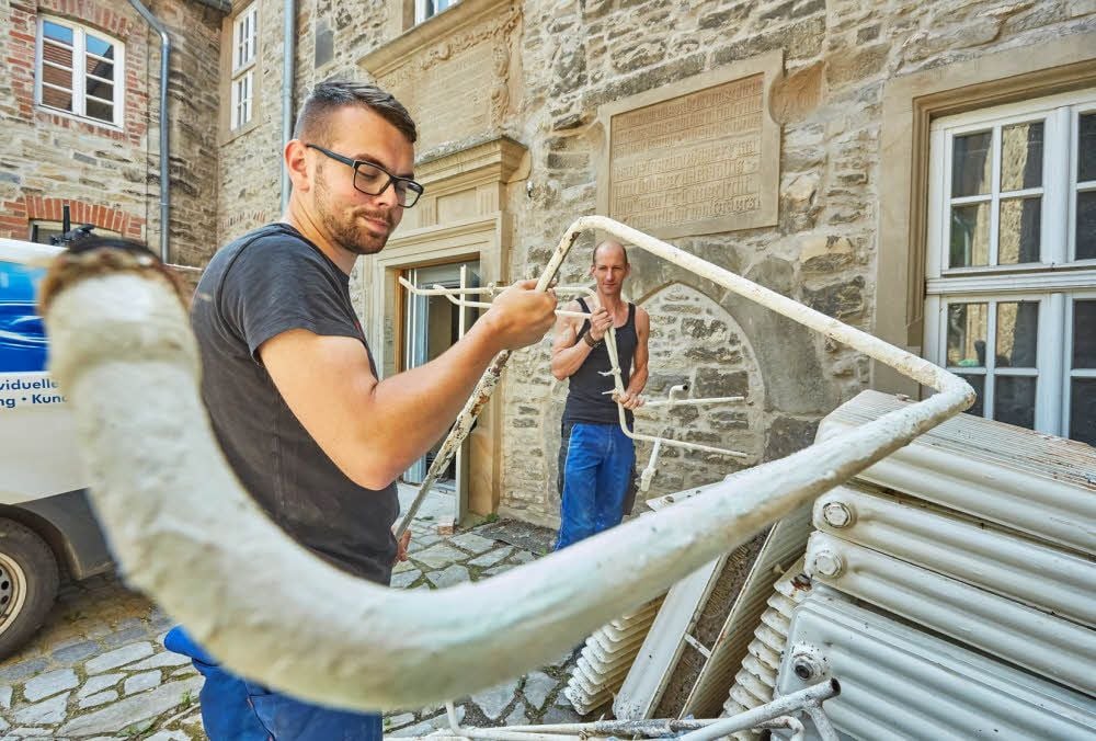 Die Heizungsbauer John Karstedt (v. li.) und Michael Brandt entfernen die alten Heizkörper aus dem Gebäude.